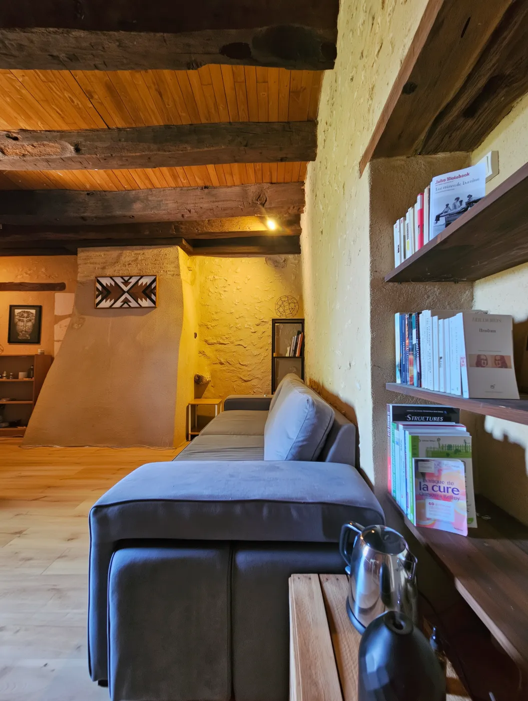 Coin salon de la chambre : canapé et bibliothèque, pierre apparente